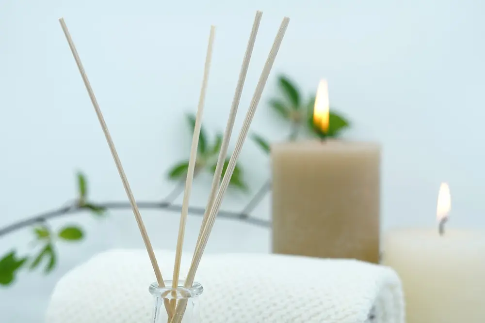 Spa items: candles, a reed diffuser and a rolled towel
